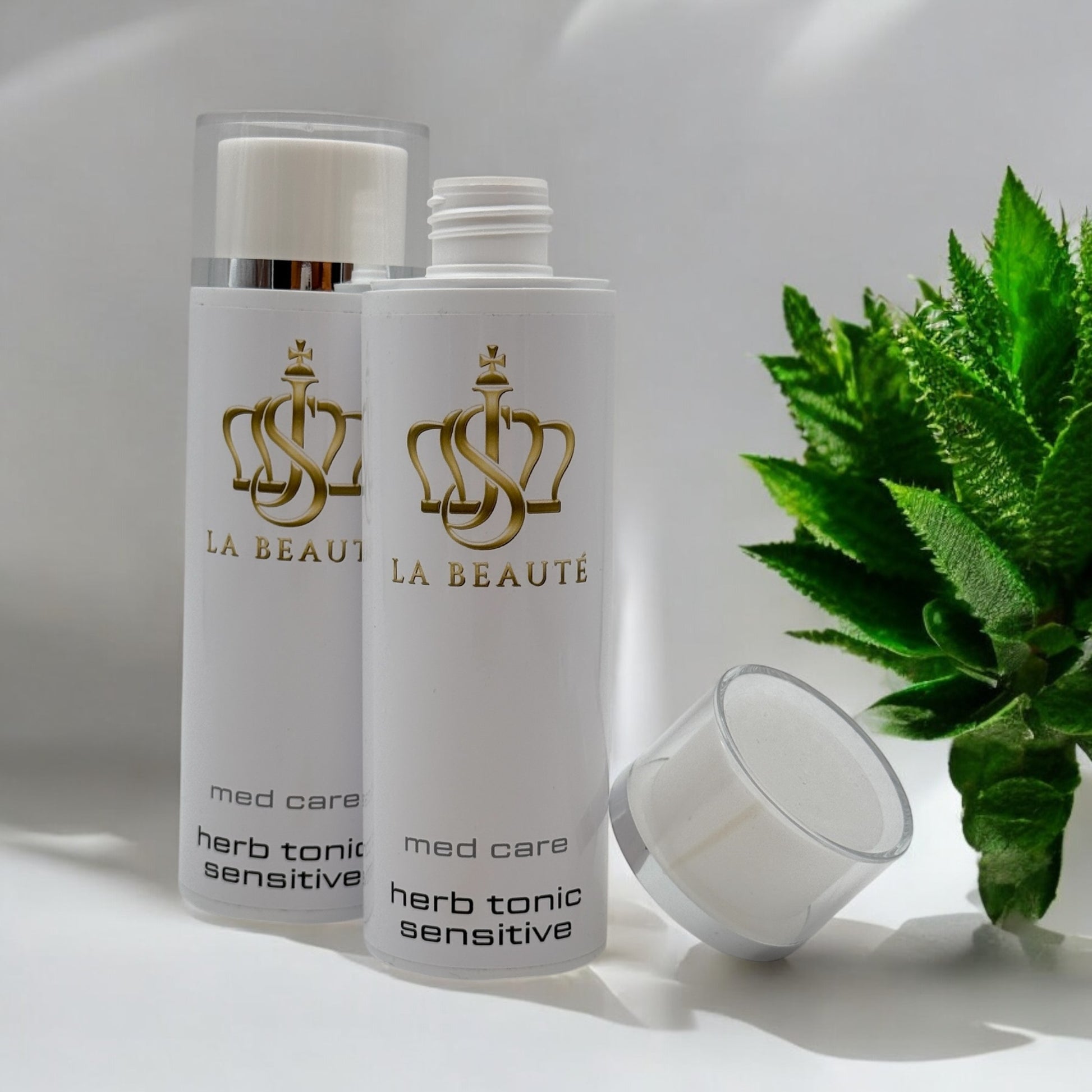 Flasche der JS La Beauté Herb tonic sensitive aus der Med Care Serie mit Drehverschluss – schlankes Design in Weiß mit Pflanzen im Hintergrund und goldfarbenem Logo.