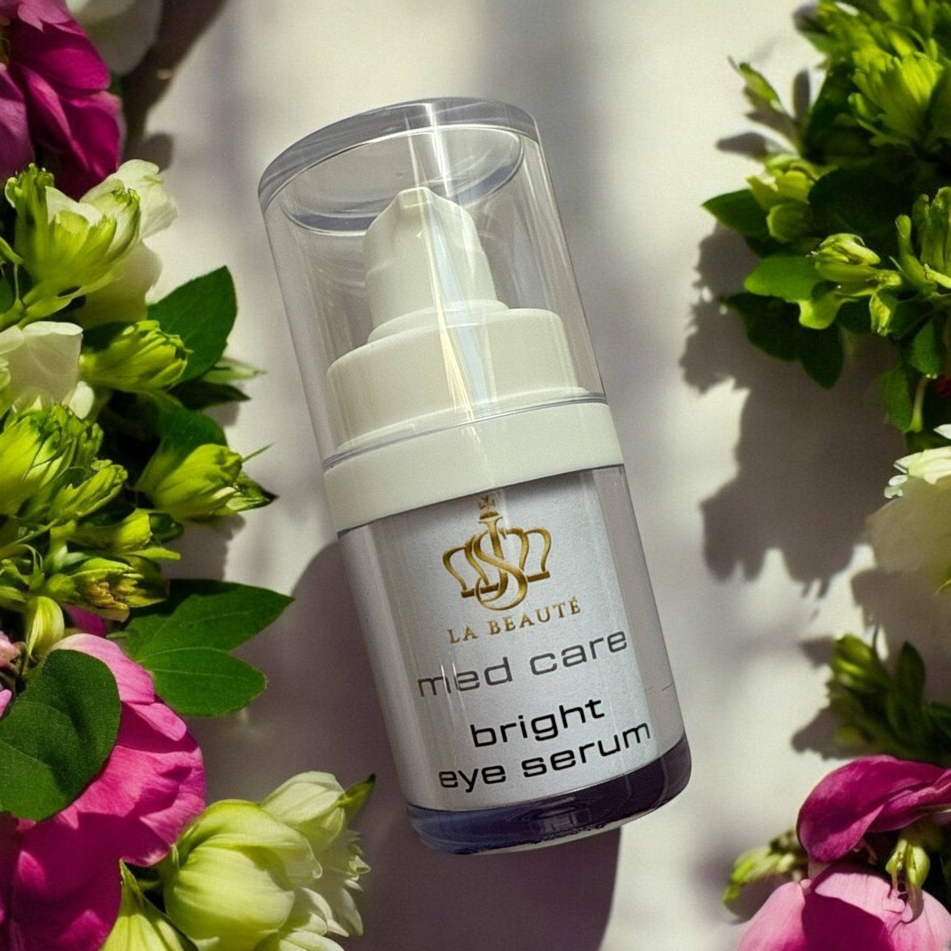 Flasche der JS La Beauté Bright Eye Serum aus der Med Care Serie mit Pumpspender – schlankes Design in Weiß Blumen an den Seiten und goldfarbenem Logo.