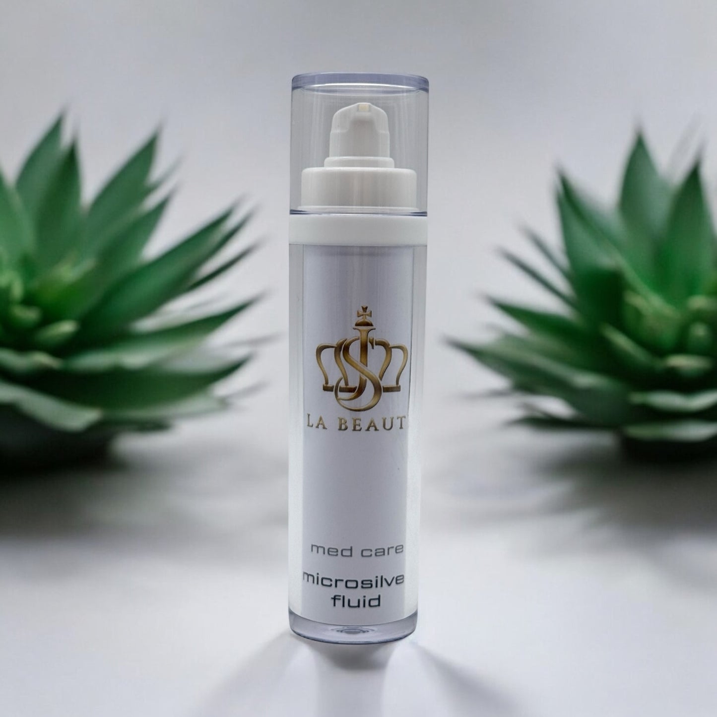 Flasche der JS La Beauté Microsilver Fluid aus der Med Care Serie mit Pumpspender – schlankes Design in Weiß mit Pflanzen im Hintergrund und goldfarbenem Logo.