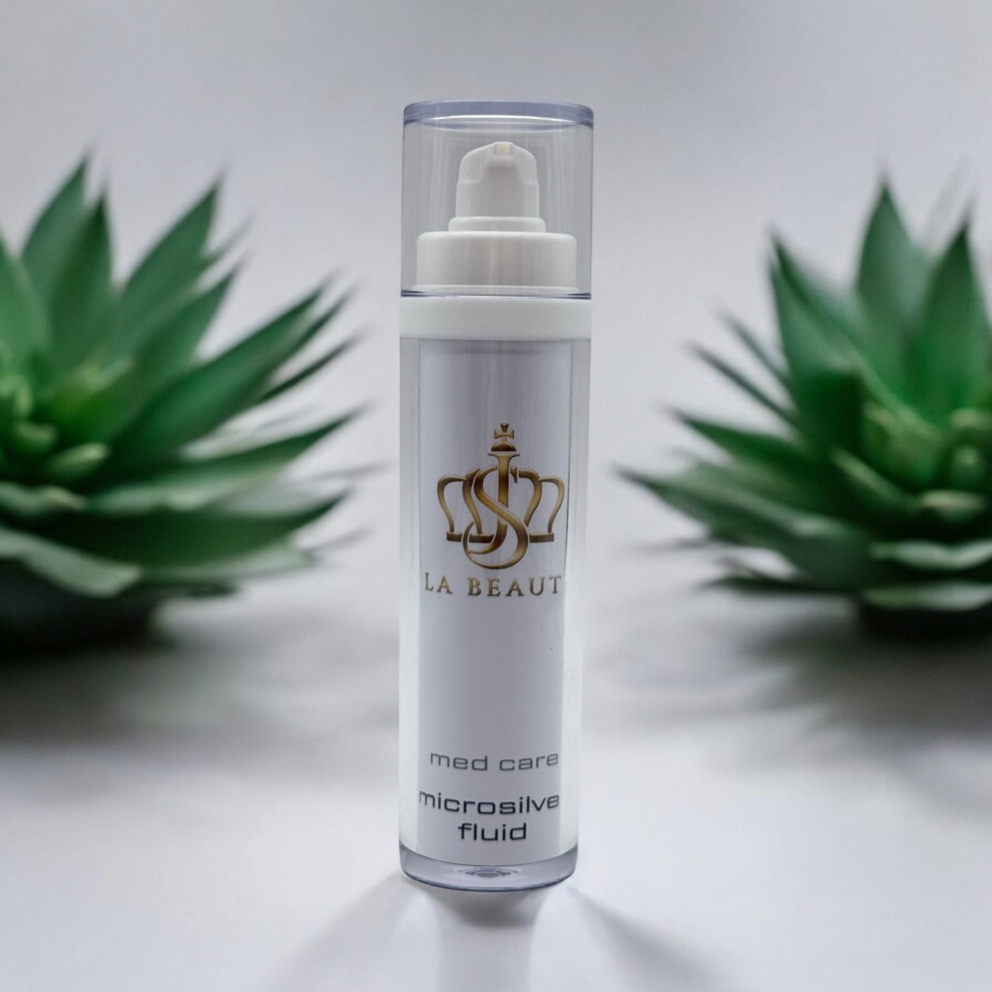 Flasche der JS La Beauté Microsilver Fluid aus der Med Care Serie mit Pumpspender – schlankes Design in Weiß mit Pflanzen im Hintergrund und goldfarbenem Logo.