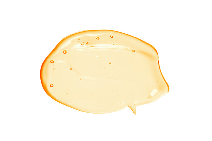 Orangefarbenes Serum als tropfen mit einem weißen Hintergrund