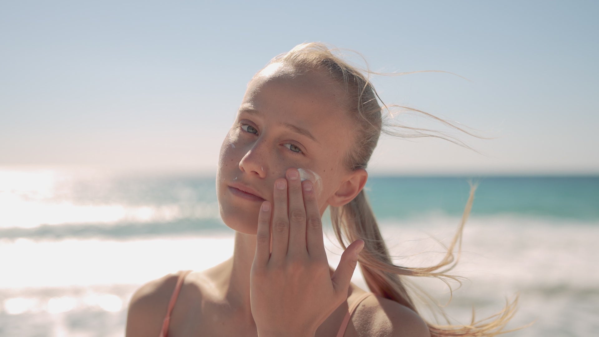 Junge Dame am Meer, welche sich eincremt